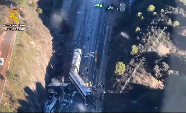 In this aerial view grab taken from video provided by Guardia Civil, a view of the Alvia train with rescue workers at the scene after a high-speed train collision, near Adamuz, Spain, Monday, Jan. 19, 2026. (Guardia Civil via AP)