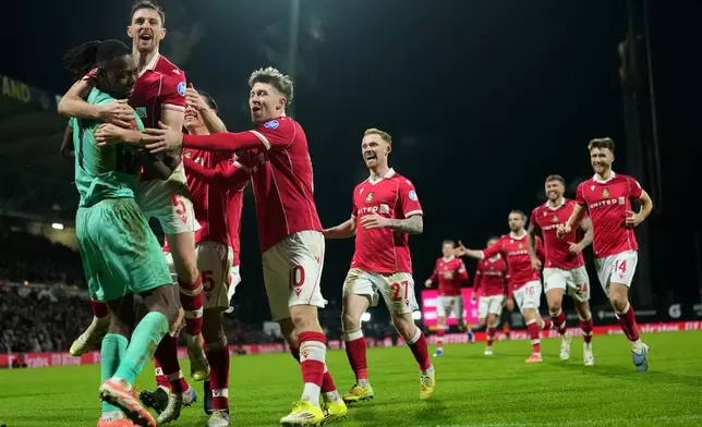 Wrexham's goalkeeper Arthur Okonkwo, left, celebrates with teammates after a penalty shootout at the end of the English FA Cup third round soccer match between Wrexham and Nottingham Forest in Wrexham, Wales, Friday, Jan. 9, 2026. (AP Photo/Jon Super)