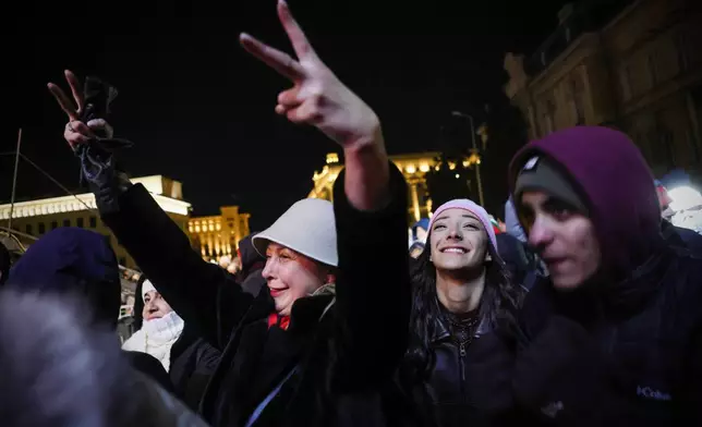 Bulgarians sing and shout as they celebrate the New Year and Bulgaria's adoption of the euro in front of the Bulgarian National Bank in Sofia, Bulgaria, Wednesday, Dec. 31, 2025. (AP Photo/Valentina Petrova)