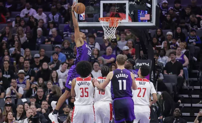 Sacramento Kings center Dylan Cardwell (32) goes yup to dunk during the first half of an NBA basketball game against the Washington Wizards, Friday, Jan. 16, 2026, in Sacramento, Calif. (AP Photo/Scott Marshall)