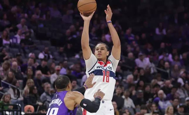 Washington Wizards forward Kyshawn George (18) looks to shoot over Sacramento Kings guard Russell Westbrook (18) during the first half of an NBA basketball game Friday, Jan. 16, 2026, in Sacramento, Calif. (AP Photo/Scott Marshall)