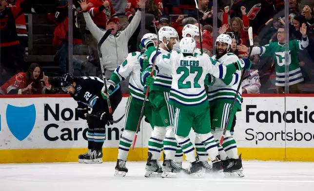 Carolina Hurricanes players celebrate after the winning goal by Jordan Staal with Utah Mammoth's Jack McBain (22) nearby during the third period of an NHL hockey game in Raleigh, N.C., Thursday, Jan. 29, 2026. (AP Photo/Karl DeBlaker)