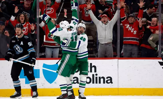 Carolina Hurricanes' Jordan Staal (11) is celebrates after his winning goal with teammate Jordan Martinook (48) with Utah Mammoth's Mikhail Sergachev (98) nearby during the third period of an NHL hockey game in Raleigh, N.C., Thursday, Jan. 29, 2026. (AP Photo/Karl DeBlaker)