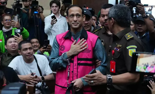 Nadiem Anwar Makarim, center, the co-founder of Indonesia's payments platform and ride hailing company Gojek and former education minister, reacts as he enters the courtroom for his first trial hearing at the Corruption Court in Jakarta, Indonesia, Monday, Jan. 5, 2026. (AP Photo/Tatan Syuflana)