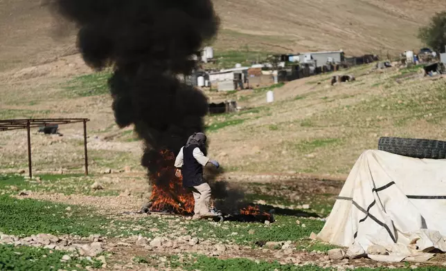 A Palestinian resident of Ras Ein al-Auja village, West Bank burns trash, Sunday, Jan. 11, 2026. (AP Photo/Mahmoud Illean)