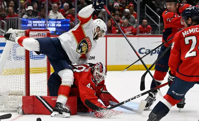 Florida Panthers left wing A.J. Greer (10) falls over Washington Capitals goaltender Logan Thompson during the second period of an NHL hockey game, Saturday, Jan. 17, 2026, in Washington. (AP Photo/John McDonnell)