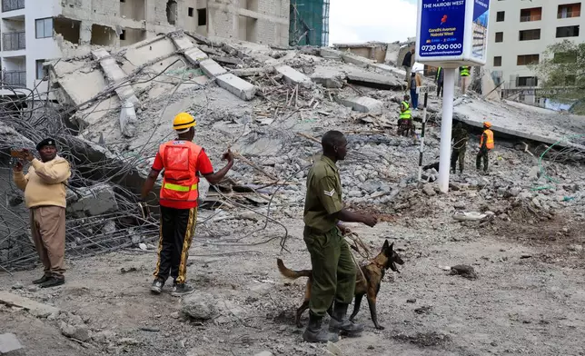 A police officer with a sniffer dog searches for survivors following the collapse of a building in Nairobi, Kenya, Friday, Jan. 2, 2026. (AP Photo/Andrew Kasuku)