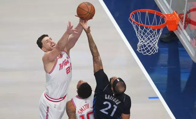 Houston Rockets center Alperen Sengun, left, goes up for a rebound against Dallas Mavericks forward Daniel Gafford (21) as teammate forward Jabari Smith Jr. (10) looks on during the first half of an NBA basketball game Saturday, Jan. 3, 2026, in Dallas. (AP Photo/Julio Cortez)