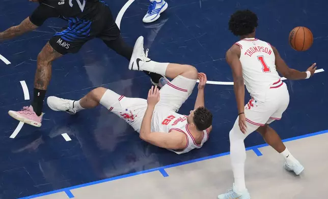 Houston Rockets center Alperen Sengun, center, falls to the floor after challenging Dallas Mavericks forward Daniel Gafford, left, for a rebound during the first half of an NBA basketball game Saturday, Jan. 3, 2026, in Dallas. (AP Photo/Julio Cortez)