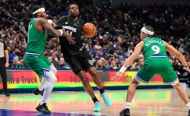 Minnesota Timberwolves' Naz Reid (11) drives to the basket as Dallas Mavericks' Jaden Hardy, left, and Ryan Nembhard (9) defend in the first half of an NBA basketball game Wednesday, Jan. 28, 2026, in Dallas. (AP Photo/Tony Gutierrez)