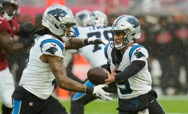 Carolina Panthers quarterback Bryce Young, right, hands off to running back Rico Dowdle (5) during the first half of an NFL football game Saturday, Jan. 3, 2026, in Tampa, Fla. (AP Photo/Chris O'Meara)