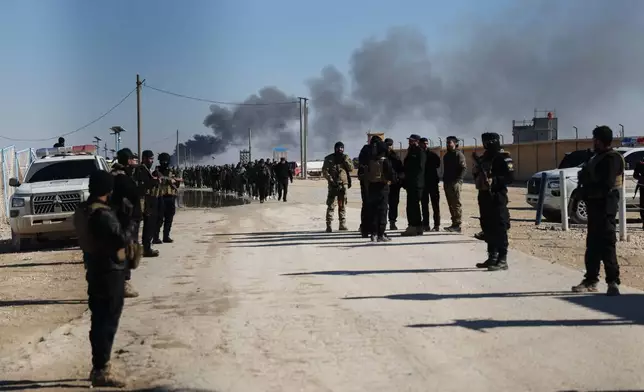 Syrian government forces patrol inside the al-Hol camp as smoke rises from an arms depot explosion in northeastern Syria's Hasakeh province, Syria, Wednesday, Jan. 21, 2026, after the withdrawal of the Syrian Democratic Forces (SDF). (AP Photo/Ghaith Alsayed)