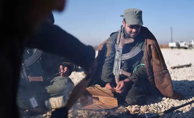 Syrian government soldiers light a small fire as they wait to enter the al-Hol camp in northeastern Syria's Hasakeh province, Syria, Wednesday, Jan. 21, 2026, after the withdrawal of the Syrian Democratic Forces (SDF). (AP Photo/Ghaith Alsayed)