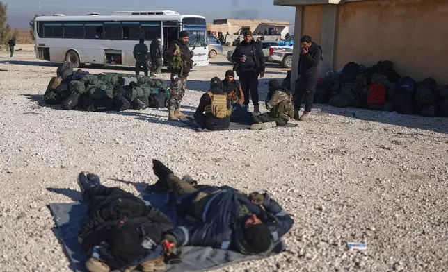 Syrian government soldiers lie on the ground as they wait with others to enter the al-Hol camp in northeastern Syria's Hasakeh province, Syria, Wednesday, Jan. 21, 2026, after the withdrawal of the Syrian Democratic Forces (SDF). (AP Photo/Ghaith Alsayed)