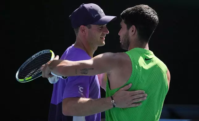 Carlos Alcaraz, right, of Spain is congratulated by Tommy Paul, left, of the U.S. during their fourth round match at the Australian Open tennis championship in Melbourne, Australia, Sunday, Jan. 25, 2026. (AP Photo/Dita Alangkara)