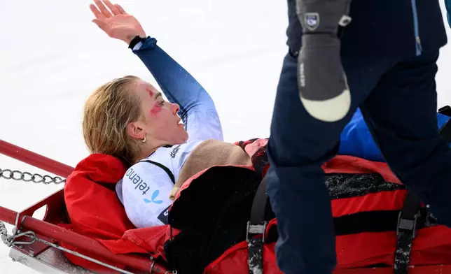 Marte Monsen of Norway salutes on the stretcher that evacuates her after a crash in the finish area during the women's Downhill race at the Alpine Skiing FIS Ski World Cup, in Crans-Montana, Switzerland, Friday, Jan. 30, 2026. (Alessandro della Valle/Keystone via AP)