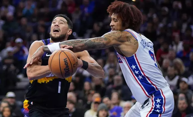 Phoenix Suns' Devin Booker, left, cannot get a shot past Philadelphia 76ers' Kelly Oubre Jr. during the first half of an NBA basketball game Tuesday, Jan. 20, 2026, in Philadelphia. (AP Photo/Matt Slocum)