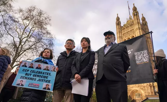 People gather in Westminster, holding a banner to protest against the new China's embassy, in London, Tuesday, Jan. 20, 2026.(AP Photo/Alberto Pezzali)
