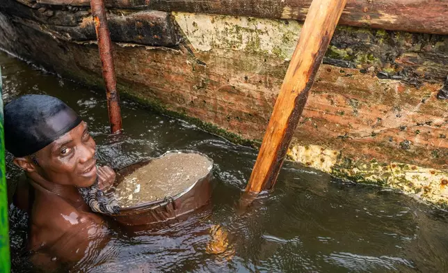 One of thousands of local dredgers diving for sand to support his household on Saturday, Dec. 13, 2025. He said he and his partner earn about 12,000 naira ($8) each per boatload, selling to a middleman who supplies larger buyers. (AP Photo/Grace Ekpu)