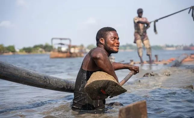 Worker shovels up freshly extracted sharp sand from dredging transporter in Ibeshe, Lagos, Nigeria, on Saturday, Dec. 6, 2025. (AP Photo/Grace Ekpu)