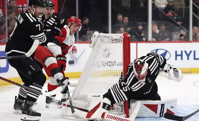 New Jersey Devils goaltender Jacob Markstrom (25) reaches for a puck against Carolina Hurricanes right wing Jackson Blake (53) during the first period of an NHL hockey game Saturday, Jan. 17, 2026, in Newark, N.J. (AP Photo/Adam Hunger)