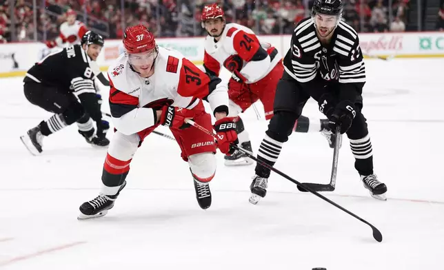 Carolina Hurricanes right wing Andrei Svechnikov (37) battles for the puckw ith New Jersey Devils center Nico Hischier (13) during the first period of an NHL hockey game Saturday, Jan. 17, 2026, in Newark, N.J. (AP Photo/Adam Hunger)