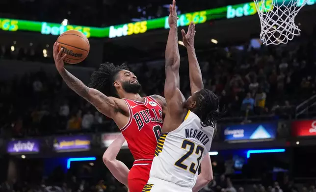 Chicago Bulls guard Coby White (0) misses a shot over Indiana Pacers guard Aaron Nesmith (23) during the second half of an NBA basketball game in Indianapolis, Wednesday, Jan. 28, 2026. (AP Photo/Michael Conroy)