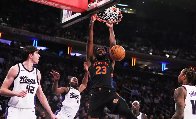 New York Knicks' Mitchell Robinson (23) dunks the ball in front of Sacramento Kings' Maxime Raynaud (42), Precious Achiuwa (9) and DeMar DeRozan during the first half of an NBA basketball game Tuesday, Jan. 27, 2026, in New York. (AP Photo/Frank Franklin II)