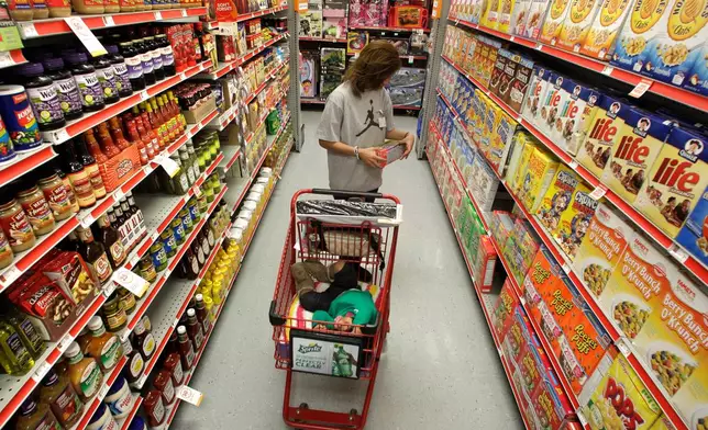 FILE - A woman looks at products in the aisle of a store as her daughter naps in the shopping cart in Waco, Texas, on Dec. 14, 2010. (AP Photo/Tony Gutierrez, File)