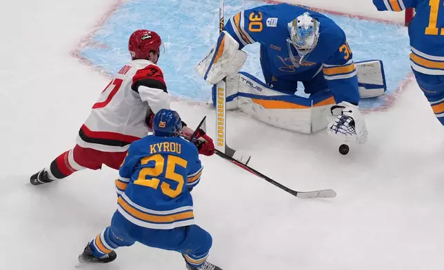 St. Louis Blues goaltender Joel Hofer (30) grabs a loose puck as teammate Jordan Kyrou (25) and Carolina Hurricanes' Andrei Svechnikov (37) watch during the second period of an NHL hockey game Tuesday, Jan. 13, 2026, in St. Louis. (AP Photo/Jeff Roberson)