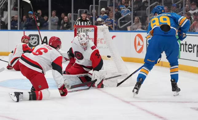 St. Louis Blues' Pavel Buchnevich (89) is unable to score past Carolina Hurricanes goaltender Brandon Bussi (32) and defenseman Mike Reilly (6) during the second period of an NHL hockey game Tuesday, Jan. 13, 2026, in St. Louis. (AP Photo/Jeff Roberson)