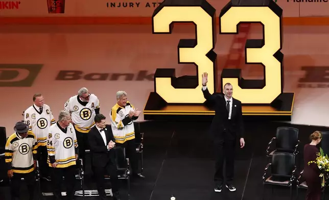 Former Boston Bruins captain Zdeno Chara, center, waves to the crowd during his number retirement ceremony, as Bruins' players with their number already retired, from left, Willie O'Ree, Rick Middleton, Terrry O'Reilly, Cam Neely, emcee Andrew Ferrance and Bobby Orr look on before an NHL hockey game between the Boston Bruins and the Seattle Kraken, Thursday, Jan. 15, 2026, in Boston. (AP Photo/Winslow Townson)