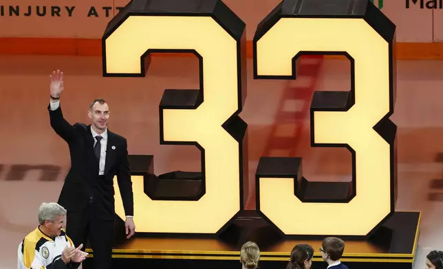Bobby Orr applauds, left bottom, as former Boston Bruins captain Zdeno Chara waves to the crowd during his number retirement ceremony before an NHL hockey game between the Boston Bruins and the Seattle Kraken, Thursday, Jan. 15, 2026, in Boston. (AP Photo/Winslow Townson)