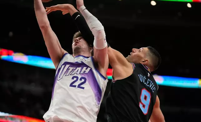 Chicago Bulls center Nikola Vucevic (9), right, blocks a shot from Utah Jazz forward Kyle Filipowski (22) during the second half of an NBA basketball game Wednesday, Jan. 14, 2026, in Chicago. (AP Photo/Erin Hooley)
