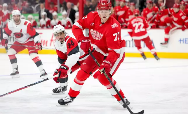 Detroit Red Wings defenseman Simon Edvinsson, right, moves the puck ahead of Carolina Hurricanes center Seth Jarvis during the first period of an NHL hockey game, Monday, Jan. 12, 2026, in Detroit. (AP Photo/Ryan Sun)