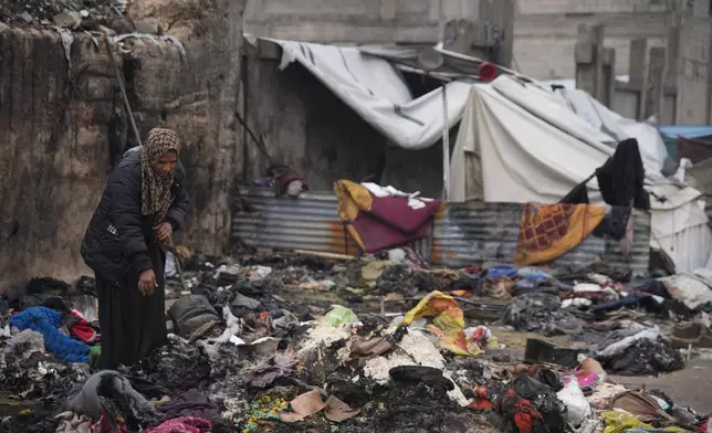Fatima Abu al-Bayd inspects what remains of her mother's tent after her mother, Amal Abu Al-Khair, and grandchild, Saud, were killed when it caught fire overnight at the Yarmouk displacement camp in Gaza City, Friday, Jan. 2, 2026. (AP Photo/Jehad Alshrafi)