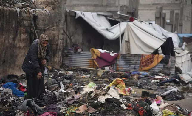 Fatima Abu al-Bayd inspects what remains of her mother's tent after her mother, Amal Abu Al-Khair, and grandchild, Saud, were killed when it caught fire overnight at the Yarmouk displacement camp in Gaza City, Friday, Jan. 2, 2026. (AP Photo/Jehad Alshrafi)