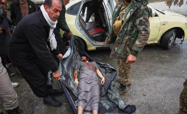Syrian government soldiers and locals carry the body of a dead civilian found by relatives in the street after government forces seized the strategic town of Taqba in eastern Syria, as part of an ongoing push against Kurdish-led forces, Sunday, Jan. 18, 2026. (AP Photo/Ghaith Alsayed)