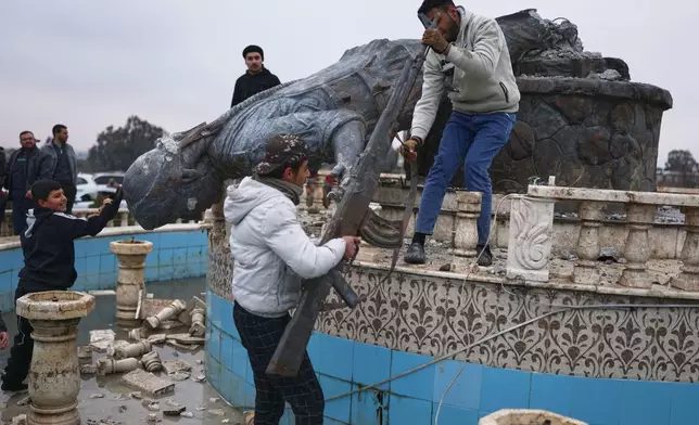 Residents topple a statue of a female Kurdish fighter after the takeover of the town by Syrian government forces from U.S.-backed Syrian Democratic Forces (SDF), in Tabqa, eastern Syria, Sunday, Jan. 18, 2026. (AP Photo/Ghaith Alsayed)