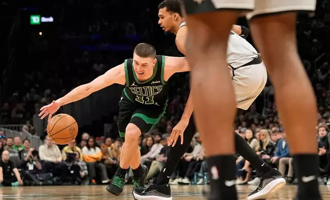 Boston Celtics guard Payton Pritchard goes low to drive by San Antonio Spurs forward Victor Wembanyama during the first half of an NBA basketball game, Saturday, Jan. 10, 2026, in Boston. (AP Photo/Robert F. Bukaty)