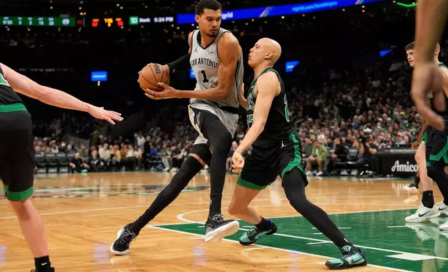 San Antonio Spurs forward Victor Wembanyama (1) drives to the basket against Boston Celtics guard Derrick White (9) during the second half of an NBA basketball game Saturday, Jan. 10, 2026, in Boston. (AP Photo/Robert F. Bukaty)