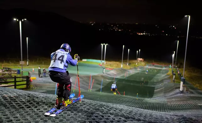 Competitors warm up before an inter-club ski meeting at Pendle Ski Club in Clitheroe, England, Tuesday, Oct. 28, 2025. (AP Photo/Jon Super)