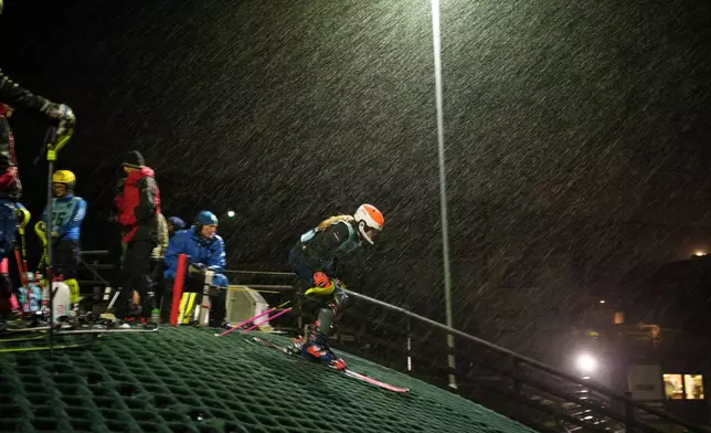 Heavy rain falls as a skier competes in a slalom race during an inter-club ski meeting at Pendle Ski Club in Clitheroe, England, Tuesday, Oct. 28, 2025. (AP Photo/Jon Super).