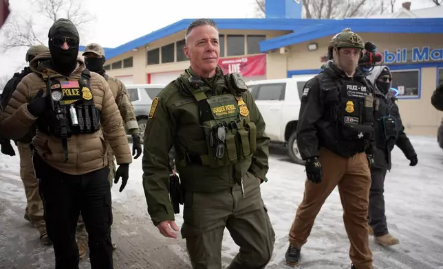 U.S. Border Patrol Cmdr. Gregory Bovino walks with Federal agents outside a convenience store on Wednesday, Jan. 21, 2026, in Minneapolis. (AP Photo/Angelina Katsanis)