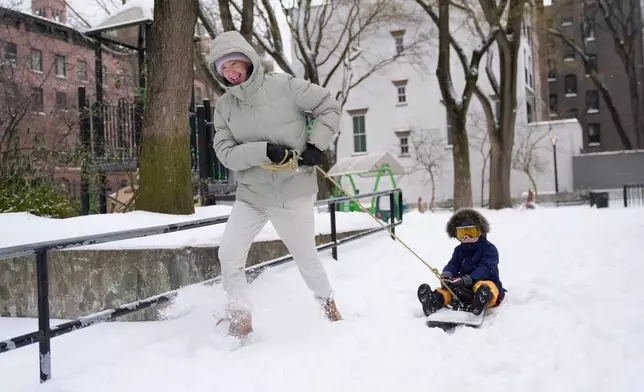 Mandy Rosenthal pulls her son Wesley, 4, on a snowboard in a small park in New York, Monday, Jan. 26, 2026. (AP Photo/Seth Wenig)