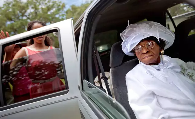 FILE - Cathleen Hillary, 93, the oldest resident of Sapelo Island, Ga. leaves a church service with her great granddaughter Milaika Ellison, for the 129th anniversary of St. Luke Baptist Church on the island on Sunday, June 9, 2013. (AP Photo/David Goldman, File)
