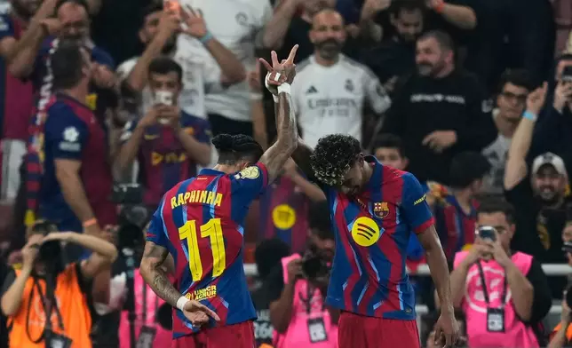 Barcelona's Raphinha, left, celebrates with teammate Lamine Yamal after scoring the opening goal during the Spanish Super Cup final soccer match against Real Madrid at King Abdullah Sports City Stadium in Jeddah, Saudi Arabia, Sunday, Jan. 11, 2026. (AP Photo/Altaf Qadri)