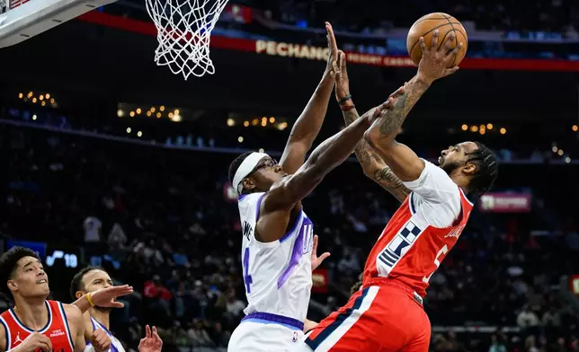 Los Angeles Clippers forward Derrick Jones Jr., right, shoots while while under pressure from Utah Jazz center Oscar Tshiebwe, center, during the first half of an NBA basketball game Thursday, Jan. 1, 2026, in Inglewood, Calif. (AP Photo/William Liang)