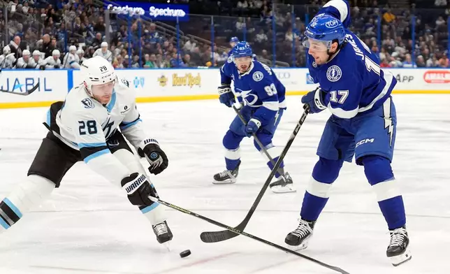 Tampa Bay Lightning center Dominic James (17) sends a pass to center Gage Goncalves (93) around Utah Mammoth defenseman Ian Cole (28) during the second period of an NHL hockey game Monday, Jan. 26, 2026, in Tampa, Fla. (AP Photo/Chris O'Meara)