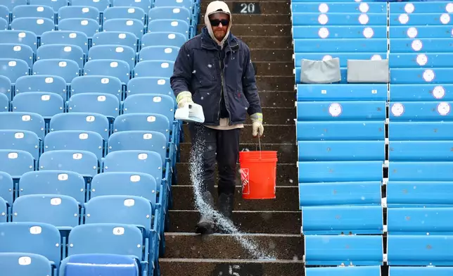FILE - Salt is applied to the steps as snow falls at Buffalo Bills Highmark Stadium before an NFL football game between the Buffalo Bills and the Cincinnati Bengals, Dec. 7, 2025, in Orchard Park, N.Y. (AP Photo/Jeffrey T. Barnes, File)